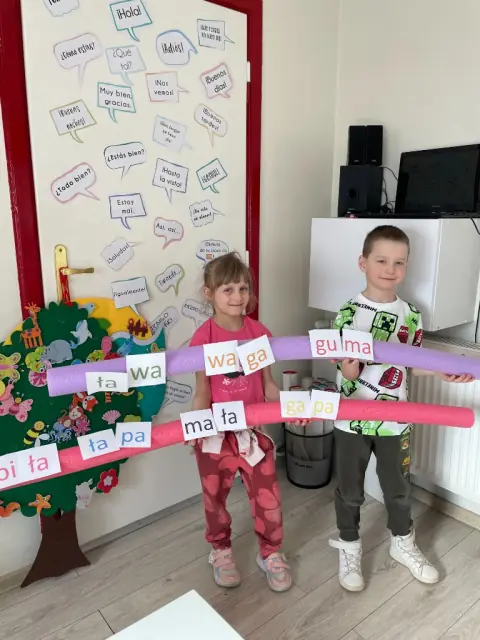 Dwoje dzieci z kartami sylab na makaronach basenowych