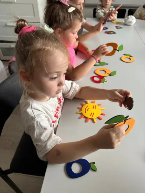 Chłopiec przenosi figurki pęsetą przy Sensory Box