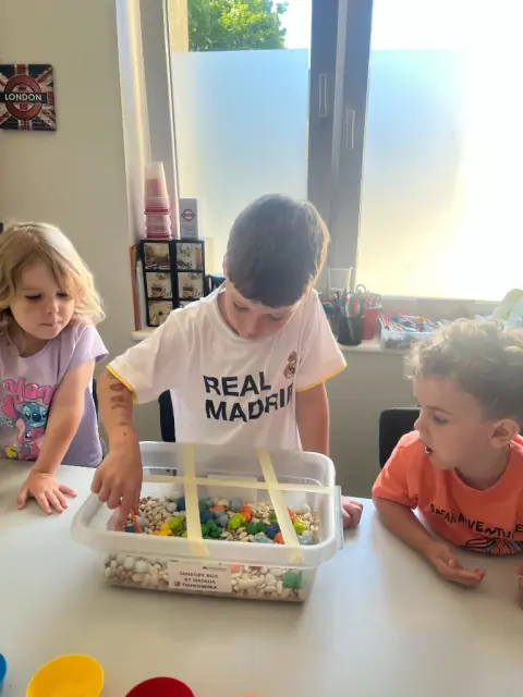 Chłopiec sięga do Sensory Box przez siatkę z taśmy