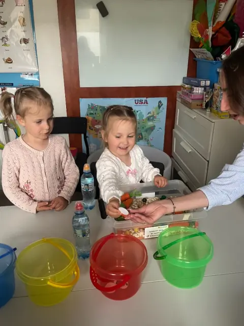 Uśmiechnięta dziewczynka wyjmuje element z Sensory Box