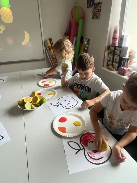 Dzieci stemplują jabłka cytrusami i farbą