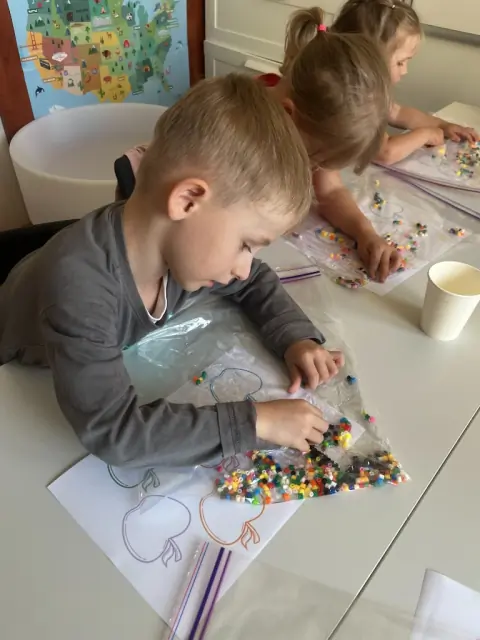 Chłopiec przesuwa koraliki w woreczku po obrysie jabłka